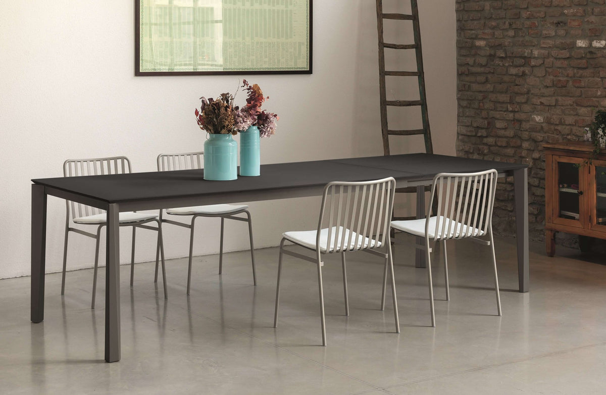 Tavolo allungabile Ingenia Prisma con piano in metallo laccato, esteso, in ambiente moderno con sedie intorno.