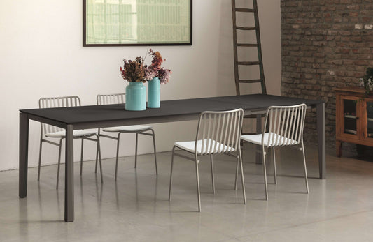 Tavolo allungabile Ingenia Prisma con piano in metallo laccato, esteso, in ambiente moderno con sedie intorno.